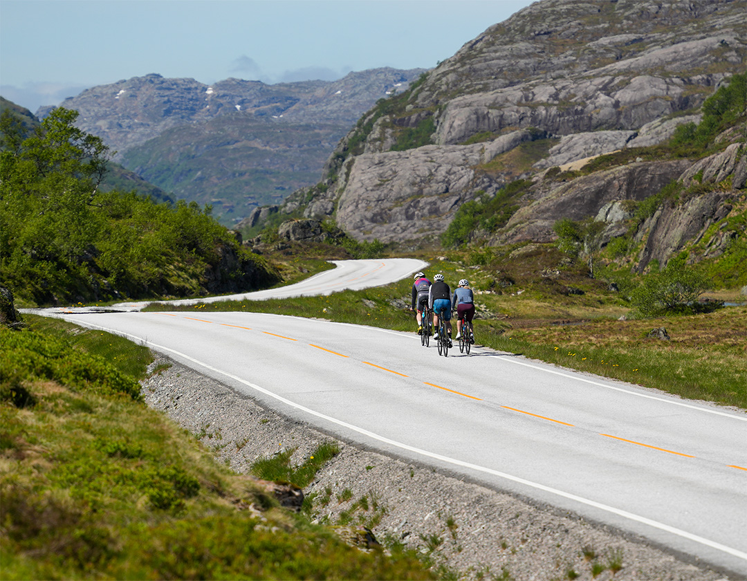 Syklister på en svingende fjellvei mellom bratte berg